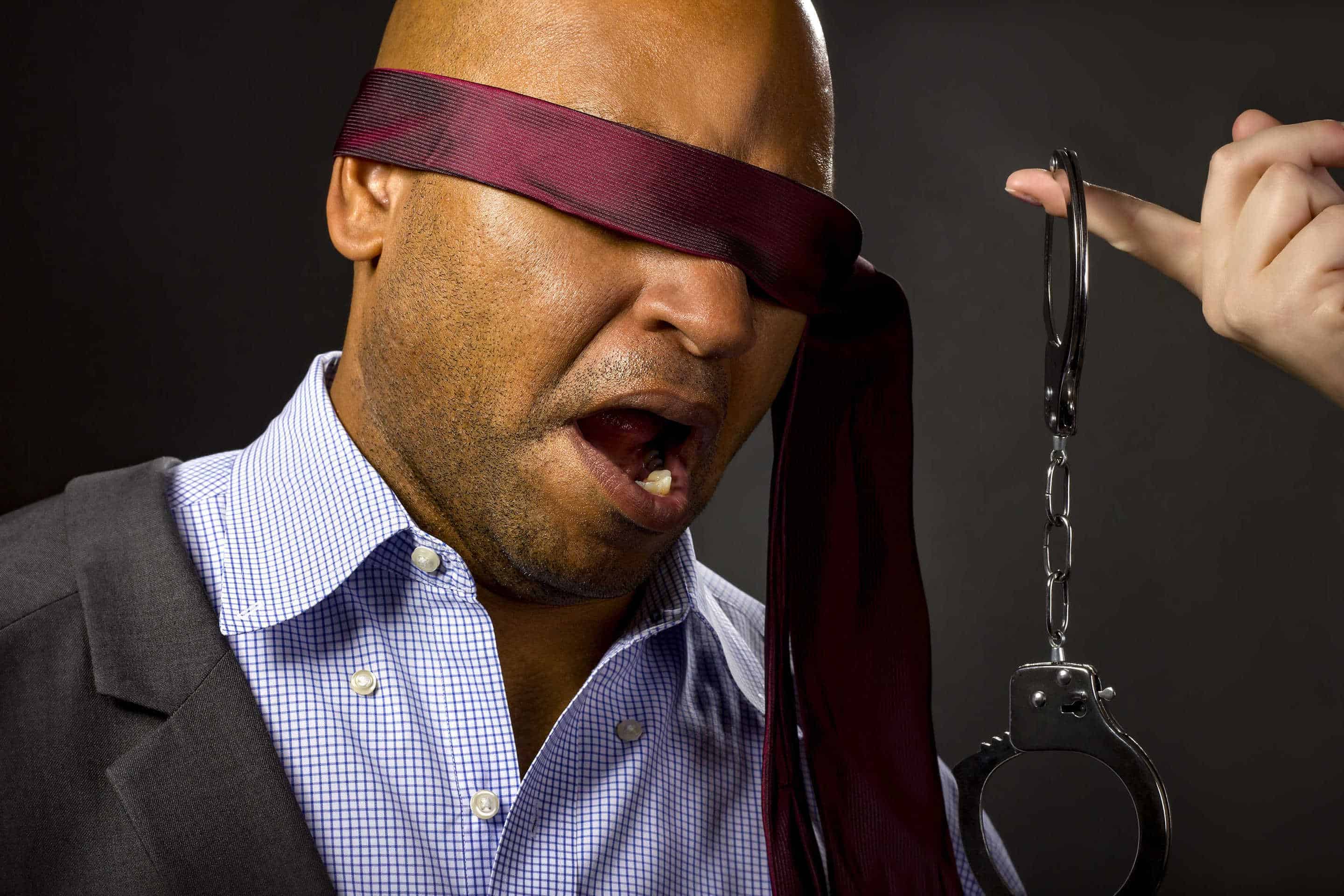 Surprised man in blindfold and handcuffs
