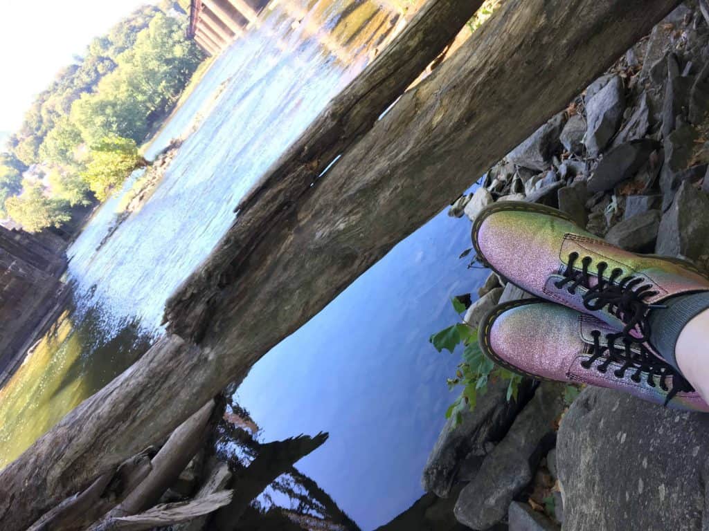 Cassie sitting next to a lake with her super gay boots on.